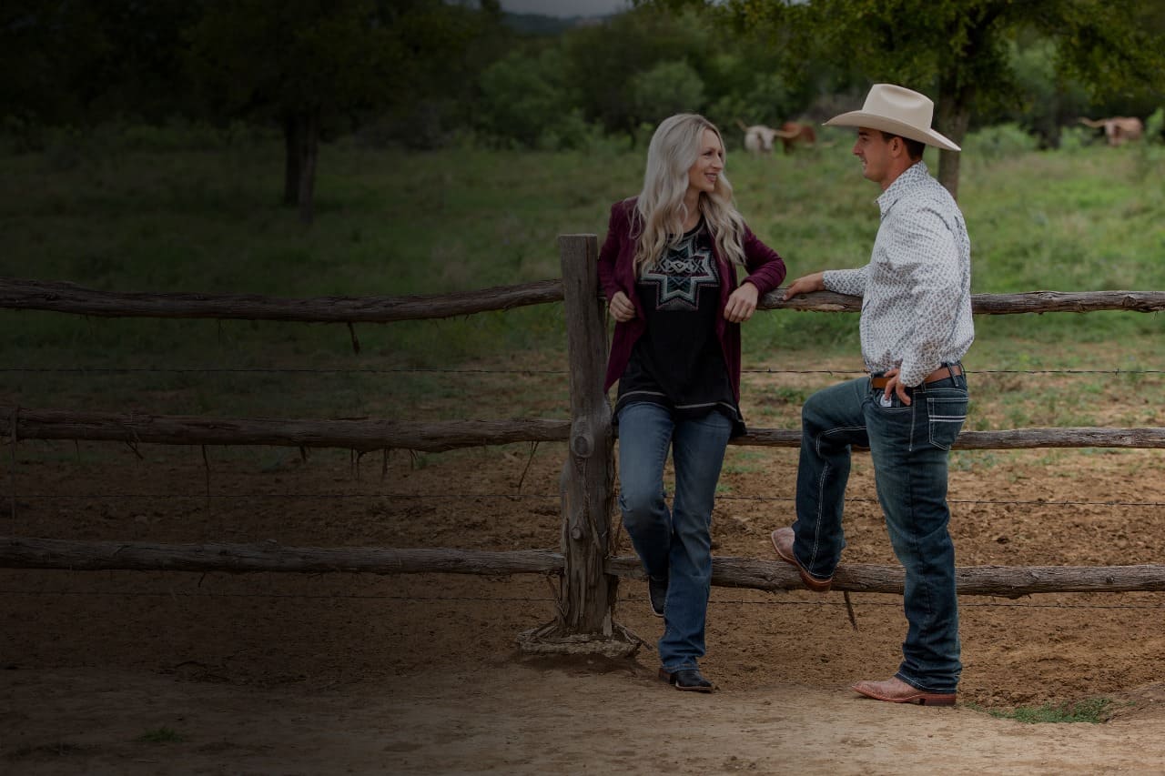 Man and women talking at a ranch wearing cowboy outfits